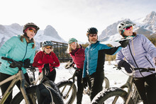 Friends Fat Biking In Snow Below Mountains