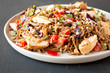 © Liudmyla - Homemade Spicy Chicken Soba Noodle Salad on a gray plate on a black surface, side view. Closeup.