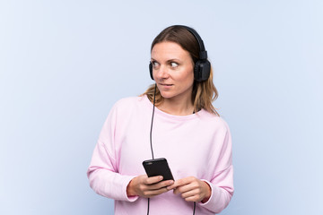 Wwoman listening music over isolated blue wall