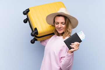 Blonde woman over isolated background in vacation with suitcase and passport