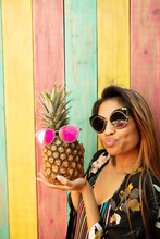 Portrait Playful, Humorous Young Woman In Sunglasses With Pineapple On Summer Patio