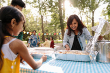 Indian Family Preparing Food On Picnic Table In Park