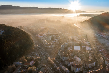 Wall Mural - Aerial view of small town in the moutains. Foggy morning with negative temperatures at sunrise.