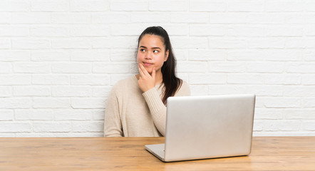 Wall Mural - Young teenager Asian girl with a laptop in a table thinking an idea