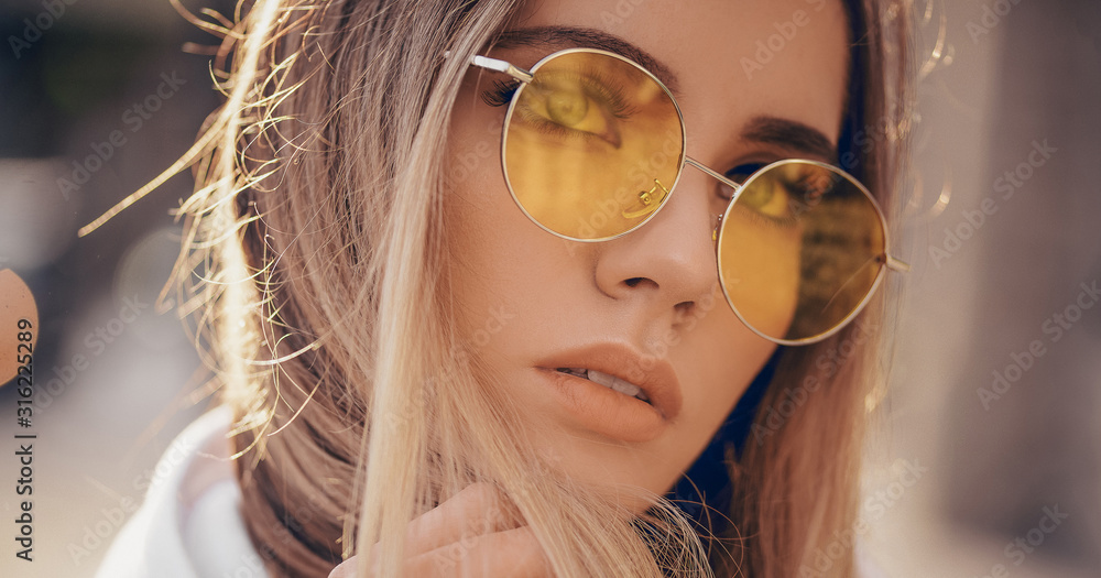 Portrait of beautiful stylish blonde woman in yellow sunglasses in outdoor. - obrazy, fototapety, plakaty 