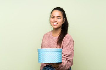 Wall Mural - Young teenager Asian girl over isolated green background holding gift box