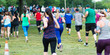 © coachwood - Rear view of many runners racing on the grass in a park