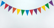 The Concept Of The Birthday In The Style Of Minimalism. A Garland Of Triangular Multicolored Paper Flags On A White Background. Free Space.