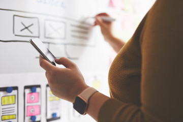 Wall Mural - web designer with mobile phone and marker drawing sketch of website on whiteboard