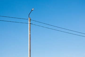 Electric pole and high voltage wires against the blue sky. Industrial landscape