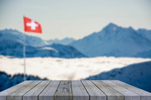 Wooden Shelf Display Table Top Against Blue Winter Mountain Panorama And Swiss Flag Snow Covered Blue Mountain Layers