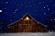 A peaceful winter scene. Evening photograph of old Weathered Barn with a peak light and falling snow captured mid flight, Eastern Oregon