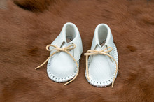 White Baby Moccasins On A Carpet Of Fur Makes A Pretty Display With Bokeh Effect.