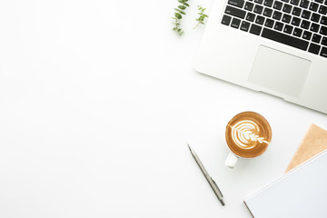Top view of white office desk table with laptop computer, cup of coffee and supplies. Minimal style, flat lay.