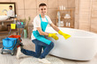 © Pixel-Shot - Male janitor doing cleanup in bathroom