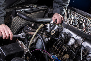 Car engine repair. Diesel engine services. Hands with a mechanic with a wrench repair Mercedes parts.