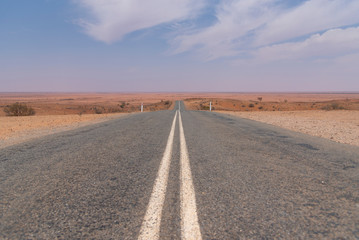 Mundi Mundi Lookout long road view with red dirt and blue sky, it’s a perfect spot to take in one of Australia’s most famous sunset Located about five kilometres North West of Silverton.