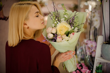 Blond girl enjoying bouquet of various roses