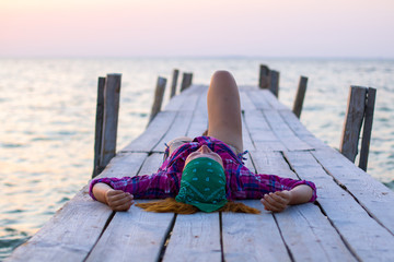 girl lying on an old wooden pier and enjoys warm evening