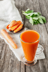 Delicious and fresh carrot juice with mint and lettuce leaves. Chilled vegetable smoothie with ice in a glass glass. Close up.