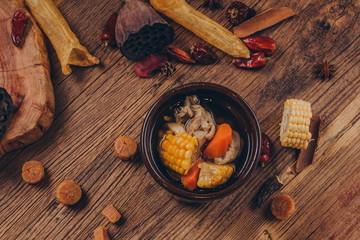 In a traditional Asian style, a black stone bowl holds a health stock made from goji berries, ginger, tripe and lobster.