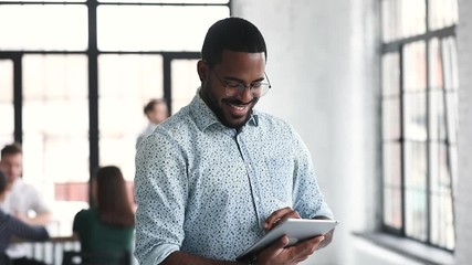 African professional businessman using digital tablet standing in office