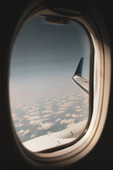 airplane window, from inside where you can see the wing and the sky with clouds