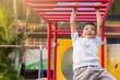 © waridsara - Soft​ focus.​ Kid exercise for health and sport concept. Happy Asian student​ child boy playing and hanging from a steel bar at the playground. 5 years old.