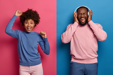 Sticker - Feeling happy and upbeat. Cheerful relaxed Afro American woman dances over pink background with hands up, overjoyed dark skinned man listens music with very loud sound, ignores everything bad