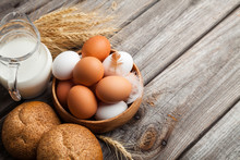 Fresh White And Brown Chicken Eggs In A Wooden Bowl, Milk, Bread, And Wheat Ears. Raw Eggs On Wooden Background