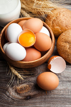 Raw Broken Egg With Yolk In A Wooden Bowl. Fresh White And Brown Chicken Eggs On Wooden Background