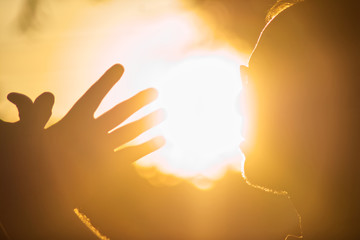 Silhouette of man and hands against the sun