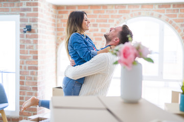 Young beautiful couple hugging at new home around cardboard boxes