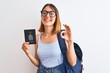 © Krakenimages.com - Beautiful redhead student woman wearing backpack and holding passport of canada doing ok sign with fingers, excellent symbol