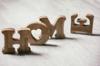 © Natasha Breen - Wooden decorative letters word HOME standing and lying on grey texture table. Concept of love or loss home