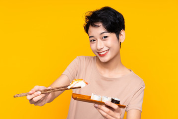 Young Asian girl with sushi over yellow background