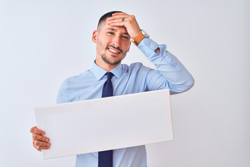 Young business man holding blank banner over isolated background stressed with hand on head, shocked with shame and surprise face, angry and frustrated. Fear and upset for mistake.