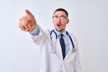 Sticker - Young doctor man wearing stethoscope over isolated background Pointing with finger surprised ahead, open mouth amazed expression, something on the front