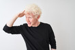 © Krakenimages.com - Young albino blond man wearing black t-shirt standing over isolated white background very happy and smiling looking far away with hand over head. Searching concept.
