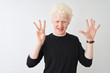 © Krakenimages.com - Young albino blond man wearing black t-shirt standing over isolated white background showing and pointing up with fingers number eight while smiling confident and happy.