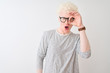© Krakenimages.com - Young albino blond man wearing striped t-shirt and glasses over isolated white background doing ok gesture shocked with surprised face, eye looking through fingers. Unbelieving expression.