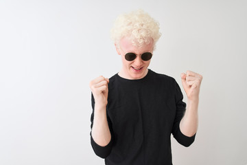 Wall Mural - Young albino man wearing black t-shirt and sunglasess standing over isolated white background celebrating mad and crazy for success with arms raised and closed eyes screaming excited. Winner concept