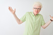 © Krakenimages.com - Young albino blond man wearing green shirt and glasses over isolated white background clueless and confused expression with arms and hands raised. Doubt concept.