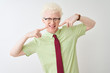 © Krakenimages.com - Young albino businessman wearing shirt and tie standing over isolated white background smiling cheerful showing and pointing with fingers teeth and mouth. Dental health concept.