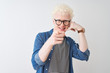 © Krakenimages.com - Young albino blond man wearing denim shirt and glasses over isolated white background smiling doing talking on the telephone gesture and pointing to you. Call me.