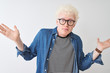 © Krakenimages.com - Young albino blond man wearing denim shirt and glasses over isolated white background clueless and confused expression with arms and hands raised. Doubt concept.