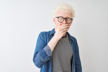 Wall Mural - Young albino blond man wearing denim shirt and glasses over isolated white background bored yawning tired covering mouth with hand. Restless and sleepiness.