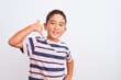 © Krakenimages.com - Beautiful kid boy wearing casual striped t-shirt standing over isolated white background smiling doing phone gesture with hand and fingers like talking on the telephone. Communicating concepts.