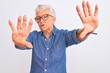 © Krakenimages.com - Senior grey-haired woman wearing denim shirt and glasses over isolated white background doing frame using hands palms and fingers, camera perspective