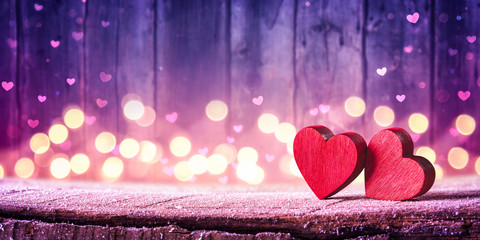 Wall Mural - two red hearts on rustic table with soft lights on wooden background - valentine's day concept